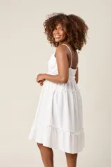 Vestido corto lila con breteles finos, escote en V con botones y falda escalonada con volados.