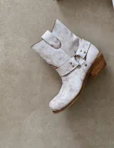 Bota tejana negra de cuero vacuno con punta cuadrada, caña media y tira con hebilla metálica alrededor del tobillo.