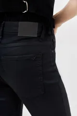 Jean de tiro medio-alto, calce skinny, con proceso de coating de acabado símil cuero y pierna al cuerpo hasta el tobillo.