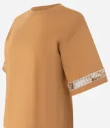 Blusa boxy de mangas cortas amplias, confeccionada en algodón, con cuello redondo y detalle de entremedios en las mangas.