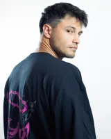 Remera negra de algodón con cuello redondo y mangas cortas. Presenta un estampado pequeño en el pecho con un diseño abstracto en tonos rosa y celeste.