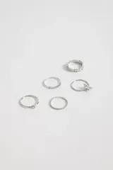 Set de anillos plateados con diferentes diseños: uno liso con una piedra, uno con una hilera de pequeñas piedras, uno con forma de estrella, uno con diseño trenzado y uno con pequeñas piedras incrustadas.