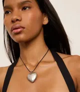 Collar corto con cordón encerado negro y colgante de corazón plateado.