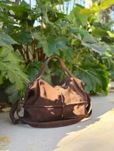 Bolso de mano tipo doctor bag color marrón, confeccionado en cuero con textura de efecto cocodrilo. Cuenta con doble asa superior, cierre metálico superior y bolsillos laterales externos.