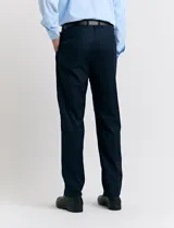 Traje de vestir color marrón topo, compuesto por saco de dos botones con solapa de muesca, dos bolsillos delanteros con solapa y un bolsillo superior. Pantalón de vestir con corte recto y bolsillos laterales. Incluye camisa blanca y corbata azul con lunares blancos.