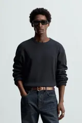 Camiseta blanca de manga larga con cuello redondo y textura cuadriculada.