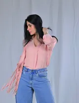 Camisa color celeste con escote en V y mangas largas con puños abotonados. Presenta detalle de flecos en el frente.