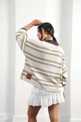 Remera de algodón y poliéster a rayas horizontales rojas y azul marino sobre fondo crudo. Tiene cuello tipo polo con botones, mangas amplias y corte oversized.