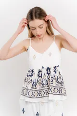 Blusa blanca de algodón con bordados artesanales en azul y beige, breteles finos y corte holgado.