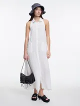Vestido largo sin mangas confeccionado en lino blanco, con cuello camisero, espalda descubierta y bordado tipo pespunte en contraste sobre el cuello.