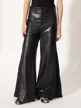 Pantalón de cuero vacuno negro, de silueta amplia con recortes diagonales en delantero y espalda. Tiene un complemento de lino al tono aplicado en los laterales.