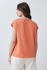 Remera color durazno con escote en V y detalle de vainillas en los laterales. De manga corta y corte recto.