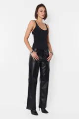 Pantalón negro de cuerina, de corte recto, tiro medio-bajo, con bolsillos delanteros y traseros, presillas en la cintura y cierre metálico.