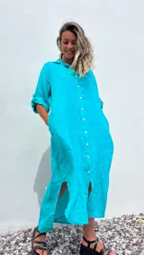 Vestido camisero largo color verde agua, confeccionado en lino 100%, con cuello camisero, abotonadura frontal completa, mangas 3/4 con trabilla y bolsillos laterales.