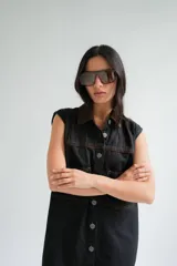 Vestido corto de jean gris con botones frontales, sin mangas, con cuello camisero y bolsillos en el pecho.