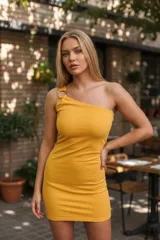 Vestido corto ajustado color amarillo mostaza, de tejido liso, con escote asimétrico de un solo hombro, sujetado por un aro metálico.