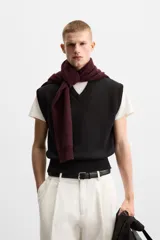 Chaleco negro de punto con cuello en V, corte cropped y sisas amplias. Tejido en hilatura de algodón con acabados en rib.