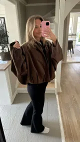 Bomber jacket color marrón de gamuza sintética, con cuello camisero, hombros caídos y elástico en la cintura.