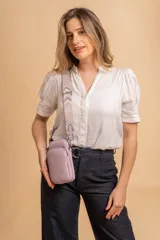 Bandolera pequeña tipo 'phone bag' de símil cuero color rosado pálido, con cierre de cremallera y correa ancha de tela con diseño de chevron en tonos claros.