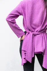 Camisa manga larga color beige con textura plumetie, abotonada en el pecho y lazo regulable que permite múltiples usos.