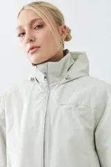 Campera impermeable gris claro con capucha plegable y bolsillos laterales.