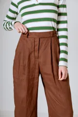 Pantalón negro de corte ancho y tiro alto, con pinzas en la cintura y bolsillos laterales.