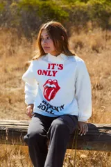 Sweater de punto grueso color blanco con cuello alto tipo mock neck y manga larga. Presenta un estampado frontal de estilo vintage con el logo de The Rolling Stones y la frase 'It's Only Rock 'N Roll' en colores rojo y negro. Confeccionado en algodón orgánico.