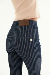 Pantalón jean de tiro alto con corte Oxford, color azul con finas rayas verticales blancas. Presenta etiqueta de cuero con logo de la marca en la parte trasera de la cintura y detalle metálico en el bolsillo trasero.