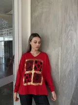 Remera roja de manga larga con cuello en V y estampado frontal con recuadros de animal print en dorado.