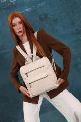Mochila mediana de símil cuero color beige, con asa superior, dos compartimentos principales con cierre y dos bolsillos frontales con cierre. Las correas son ajustables y de color beige.