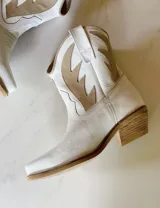 Botas cortas negras de cuero con bordados blancos estilo cowboy.