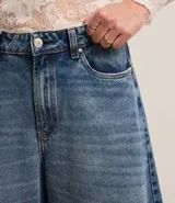 Pantalón pantalona de jeans con cintura alta, bolsillos delanteros y traseros, corte amplio y trabillas en la cintura.