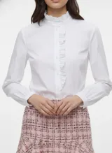 Camisa blanca de manga larga con cuello alto fruncido y tapeta de botones frontal adornada con volantes verticales.