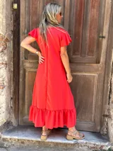 Vestido midi de seda color rojo, con escote en V, mangas cortas con volados y un amplio volado en el ruedo.