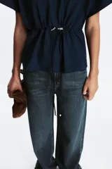 Camiseta color crudo de algodón con cuello redondo, manga corta caída y cintura ajustable con cordón.