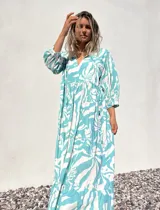 Vestido largo de corte amplio, con estampado abstracto en tonos verde agua y crudo. Tiene escote en V con lazos y mangas largas abullonadas.