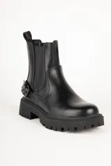 Bota de caña baja en símil cuero negro, con piezas elastizadas a los lados y hebilla metálica.