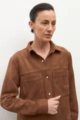 Camisa de manga larga color tostado, con cuello camisero y botones frontales. Presenta bolsillos de parche en el pecho.