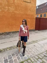 Blusa celeste y blanca a rayas verticales con cuello cuadrado, mangas largas con frunce en los hombros y corte peplum. Cierre frontal con botones. 