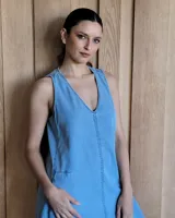 Vestido largo color crudo, sin mangas y con escote en V. Presenta aberturas laterales en el ruedo y bolsillos laterales a la altura de la cadera.