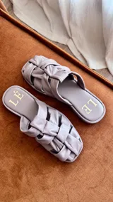 Sandalias bajas color rosa viejo con tiras de cuero entrelazadas y suela marrón.