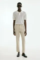 Pantalón tobillero color beige, de corte slim fit, con pliegues, cierre con botón, bolsillos laterales y bolsillos traseros ribeteados con botón.