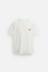 Camiseta blanca de corte recto, cuello redondo y manga corta. Estampado pequeño en el pecho con texto en rojo.
