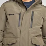 Parka color caqui con capucha, cierre frontal con cremallera y botones a presión, múltiples bolsillos con solapa y puños ajustables.