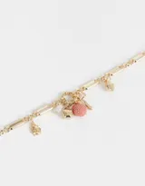Collar corto dorado con cadena de eslabones combinados y dijes colgantes de frutilla rosa brillante, hongo dorado, moño dorado y perla.