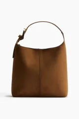 Cartera marrón de gamuza sintética con correa fina ajustable y asa ancha con hebilla metálica dorada.