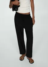Pantalón negro de tejido fluido con cintura elástica ajustable con cordón. Diseño recto de tiro alto con bolsillos laterales.