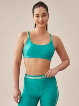 Top deportivo color turquesa con tirantes finos y banda inferior con detalle de línea horizontal en color crema.