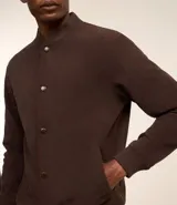 Campera bomber marrón de terciopelo pana con cuello redondo, cierre con botones a presión, bolsillos laterales, puños y cintura elastizados.