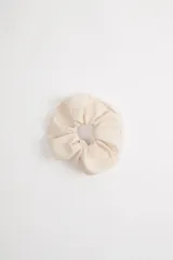 Scrunchie de tela color crudo con textura.